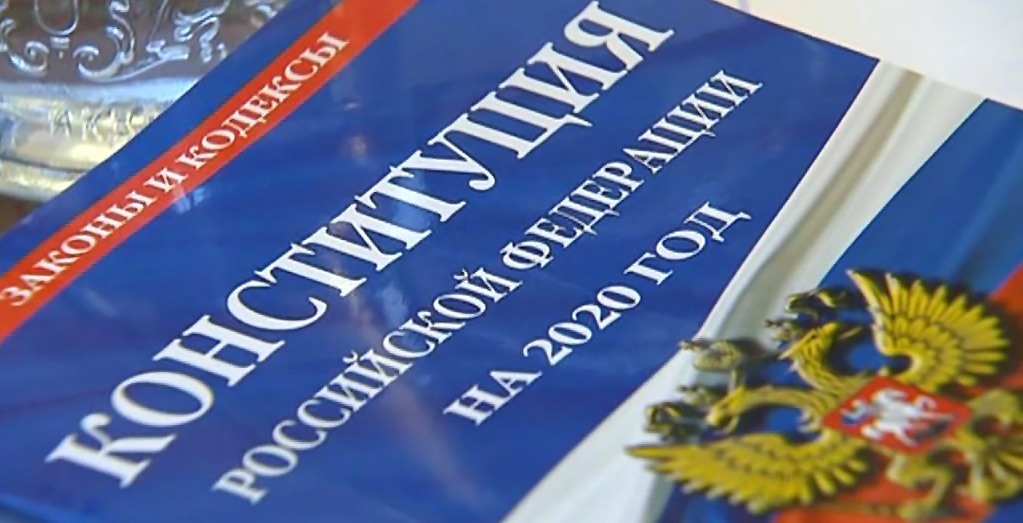 Цветное фото. Крупный план фото обложки Конституции Российской Федерации, лежащей на столе.